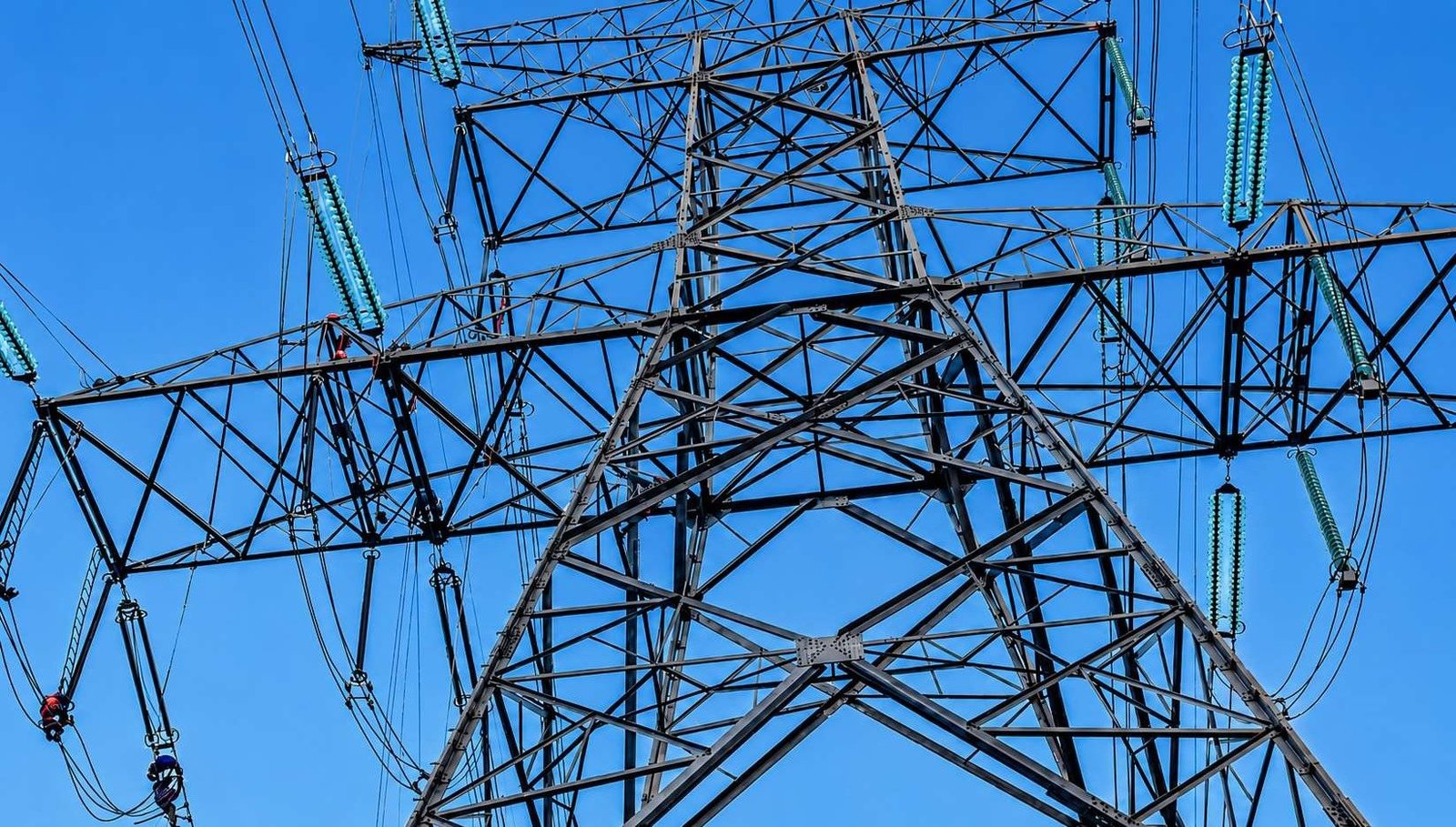 Torre de Linha de Transmissão vista de baixo, close-up dos isoladores contra o céu azul