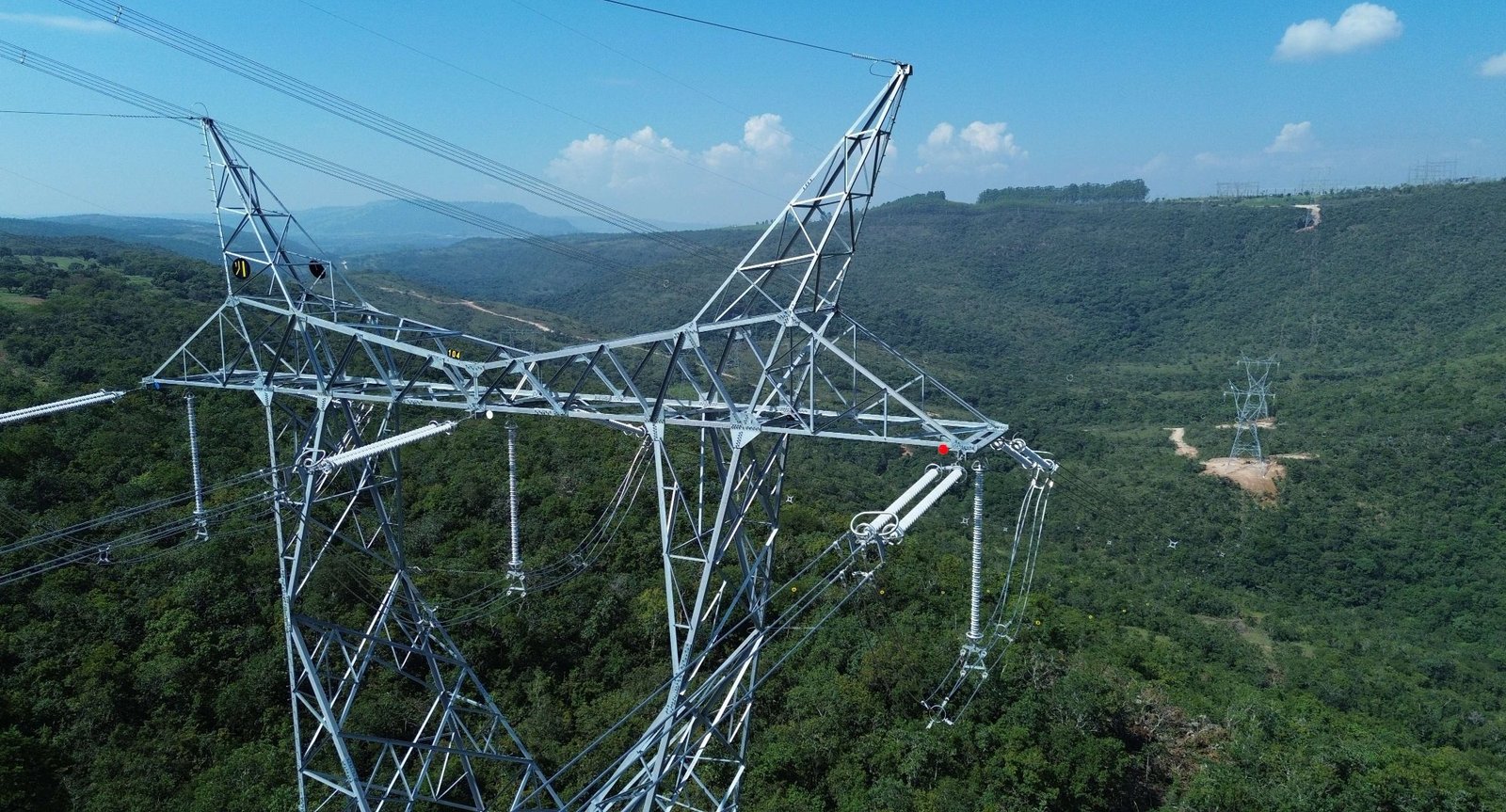 Vista aérea de torre de Linha de Transmissão sobre relevo montanhoso coberto de vegetação